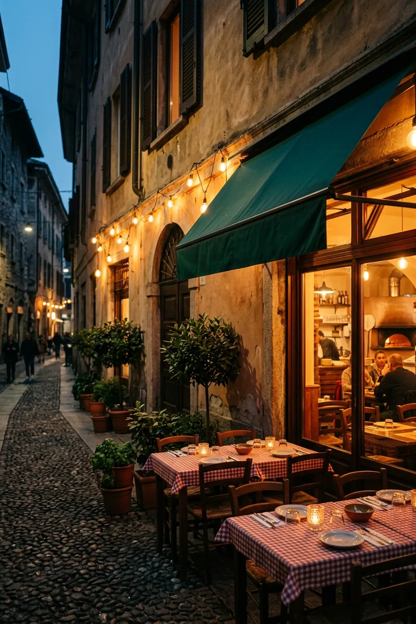 The green awning and string lights of La Brace on a cobbled Milanese street at dusk, with checked-cloth tables set outside